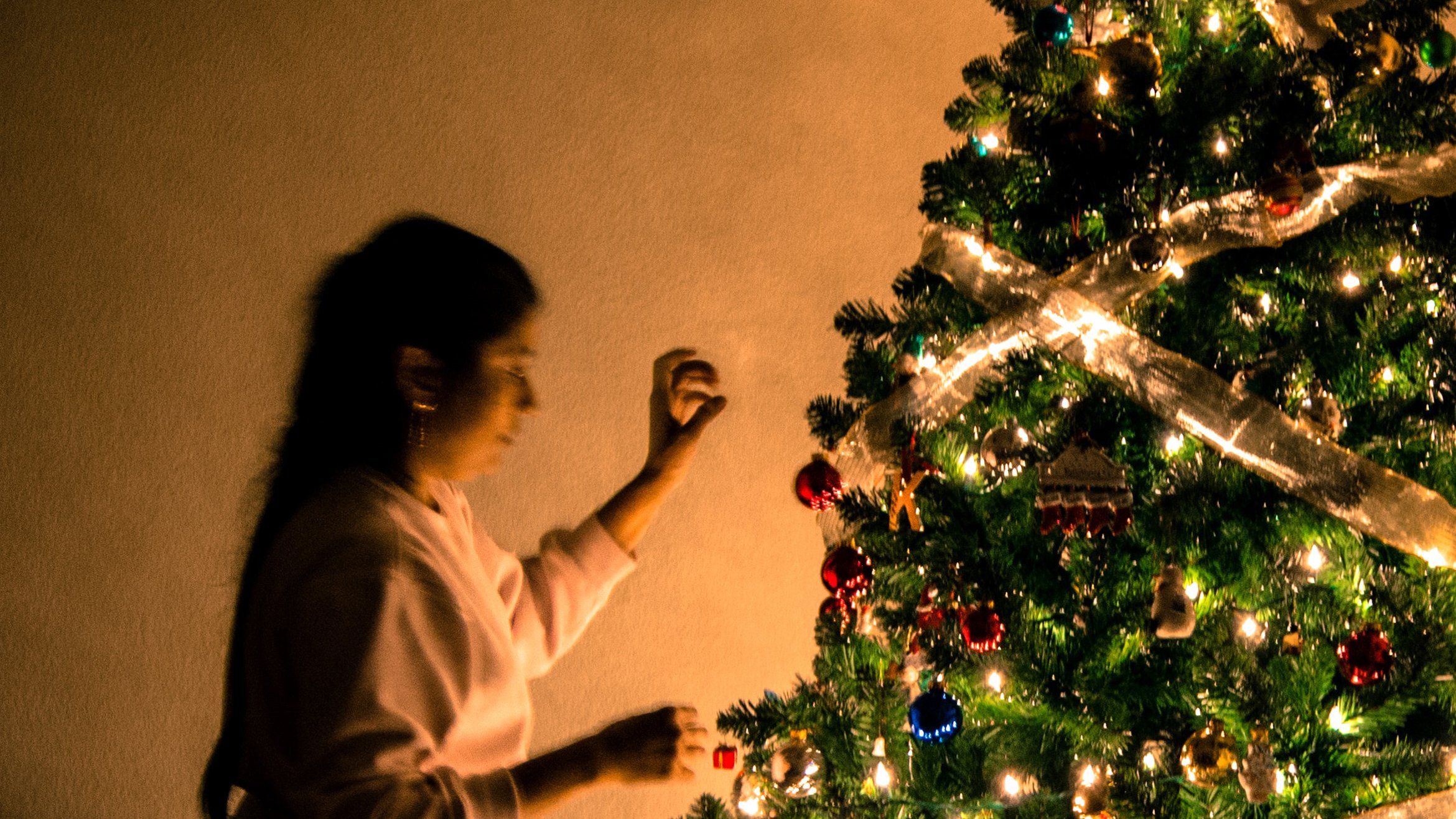 Cover Photo: A woman with dark hair is decorating a beautiful Christmas tree