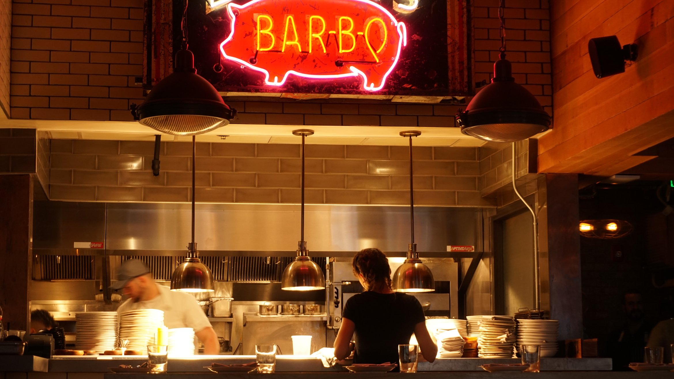 Cover Photo: This photograph shows a waitress standing waiting for an order at the kitchen, which is lit with a warm glow