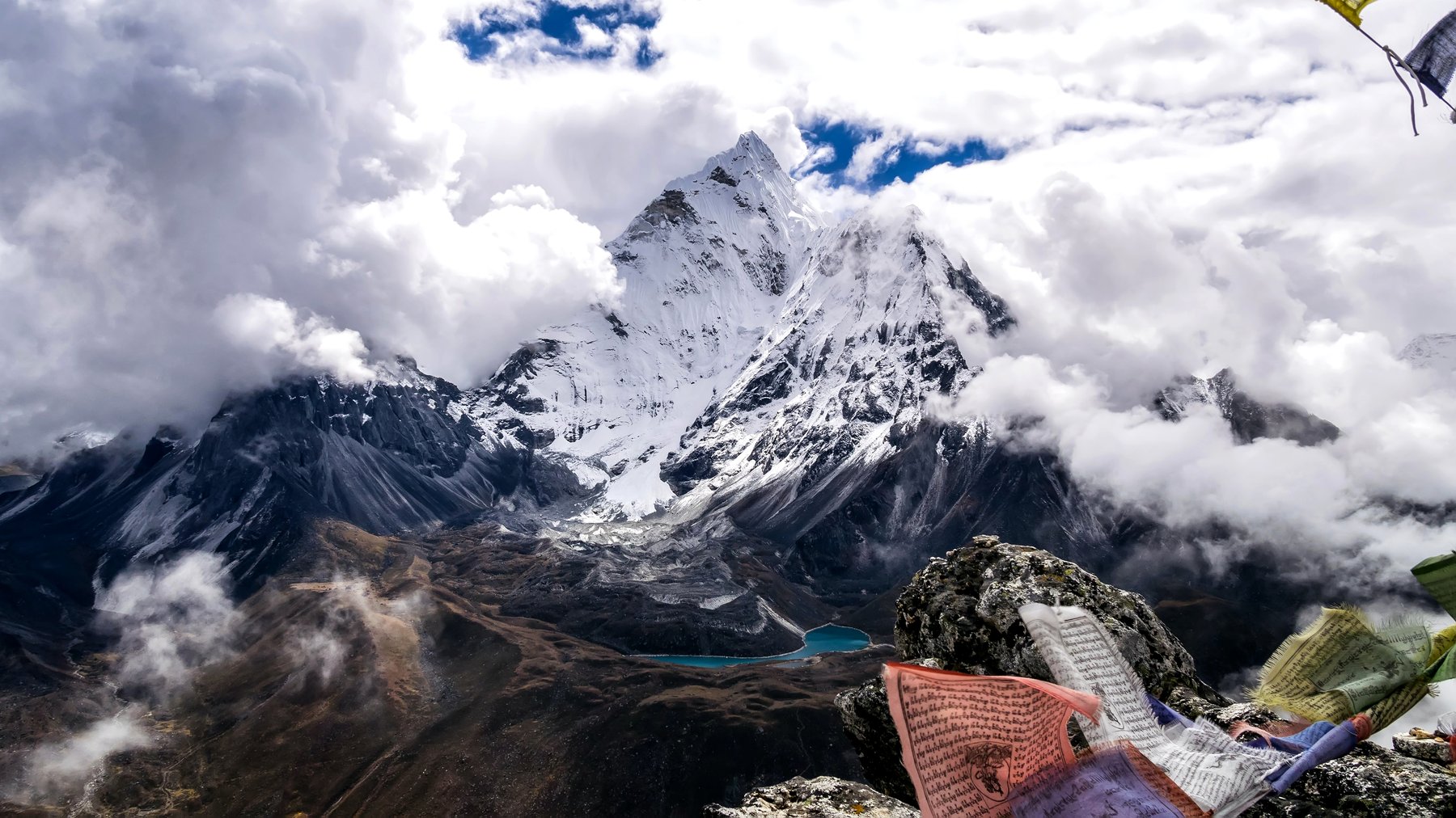 Cover Photo: snow-capped Mt. Everest wreathed in white clouds, with just a few fluttering prayer flags in the foreground