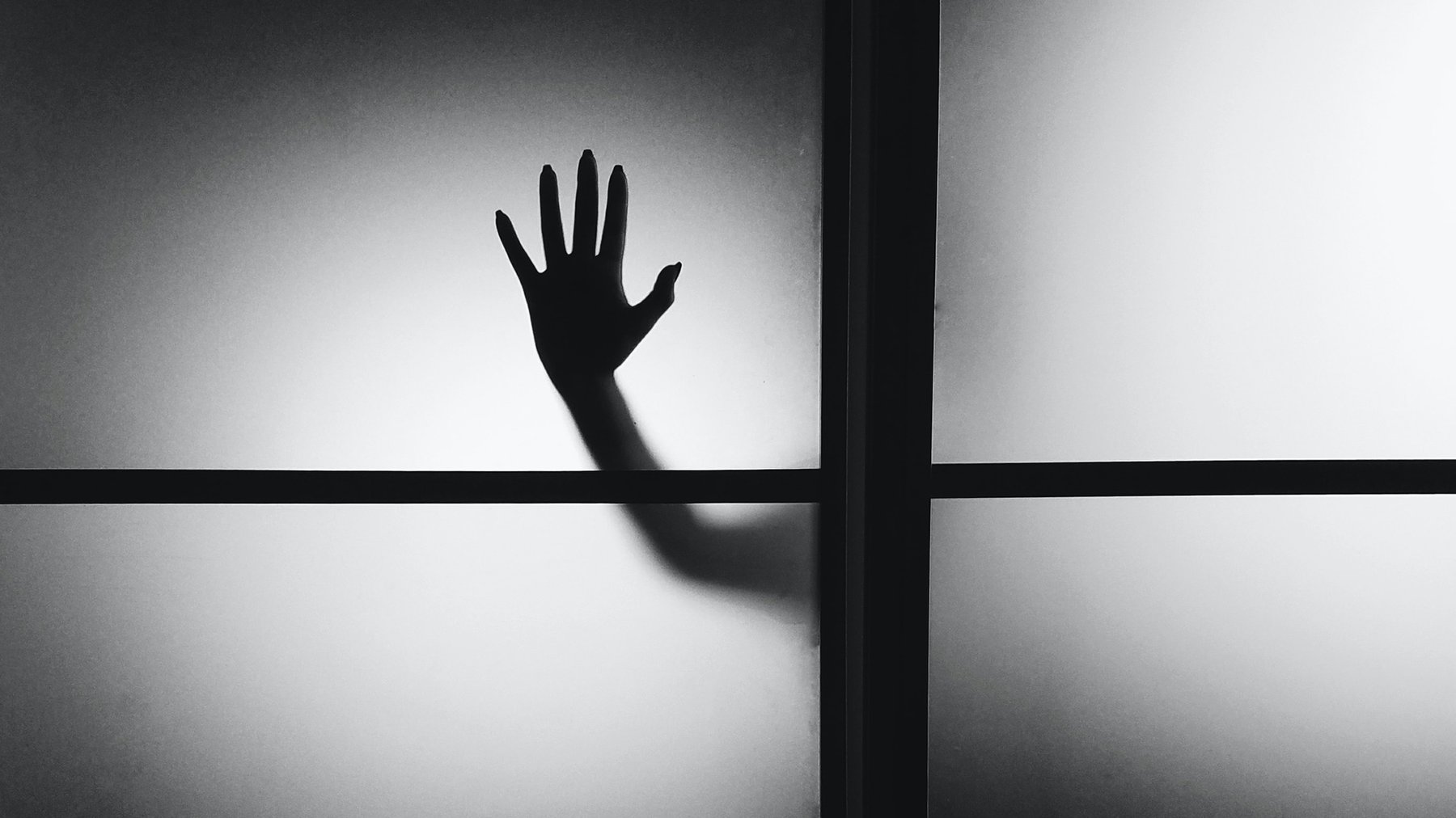 Cover Photo: The silhouette of a hand against a fogged up glass window